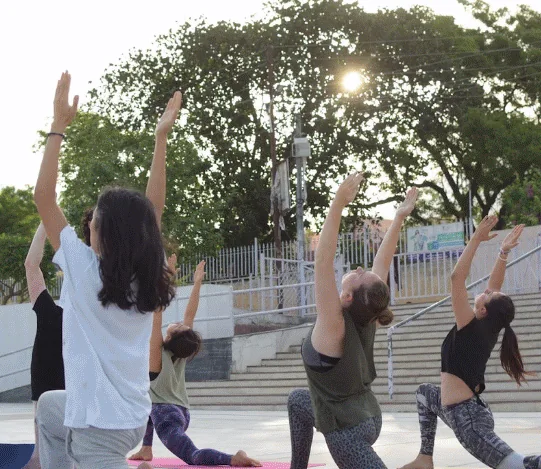 Students in warrior pose on the ghat steps in Rishikesh at sunset